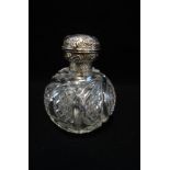 A CUT GLASS PERFUME BOTTLE with embossed silver lid