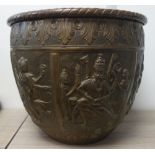 AN INDIAN KUTCH STYLE BRASS EMBOSSED JARDINIERE decorated with scenes within panels, 28cm diam