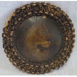 A NAIVE OIL ON BOARD OF A LION, in a cork decorated tramp-art style circular frame, circa 1900, 33.