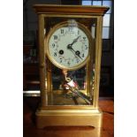 AN EDWARDIAN GILT BRASS FOUR GLASS CLOCK with compensated mercury pendulum striking on a gong,