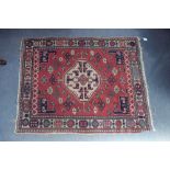 A NORTH WEST PERSIAN RUG of Kazac design, dark pink ground with single central ivory quatrefoil