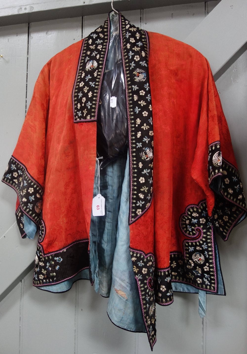 A RED SILK CHINESE JACKET with embroidered panels, blue lining, and similar textiles