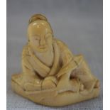 A JAPANESE CARVED IVORY NETSUKE, EDO PERIOD, EARLY 19TH CENTURY, modelled as a seated figure holding