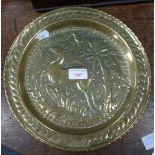 A REPOUSSE BRASS DISH decorated with a frolicking deer, in the manner of John Pearson