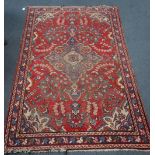 A RED GROUND PERSIAN RUG with floral motifs, 135cm x 200cm