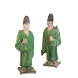 A PAIR OF CHINESE GLAZED POTTERY ATTENDANTS, MING DYNASTY, the standing figures in green flowing