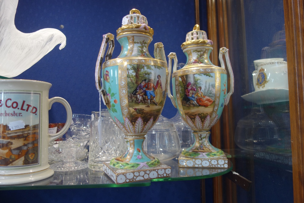 A PAIR OF 19TH CENTURY DRESDEN URNS with covers, decorated with courting couples within a green