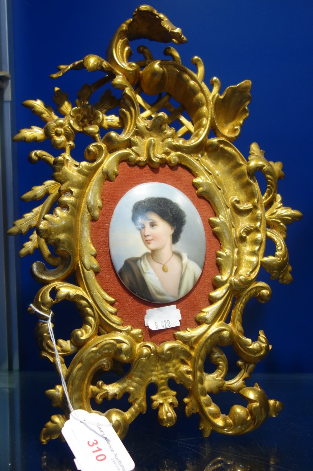 A CONTINENTAL PLAQUE OF A YOUNG WOMAN in a git cast iron rococo frame, 31cm high