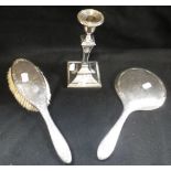 A SILVER CANDLESTICK HOLDER, together with a silver backed brush and mirror (3)