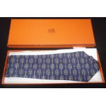 HERMES PARIS: A GENTLEMAN'S SILK TIE, decorated with motifs on a blue ground, in presentation box