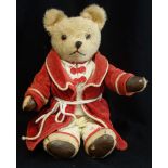 A VINTAGE PLUSH TEDDY BEAR with jointed limbs and leatherette pads, sporting a red dressing gown,