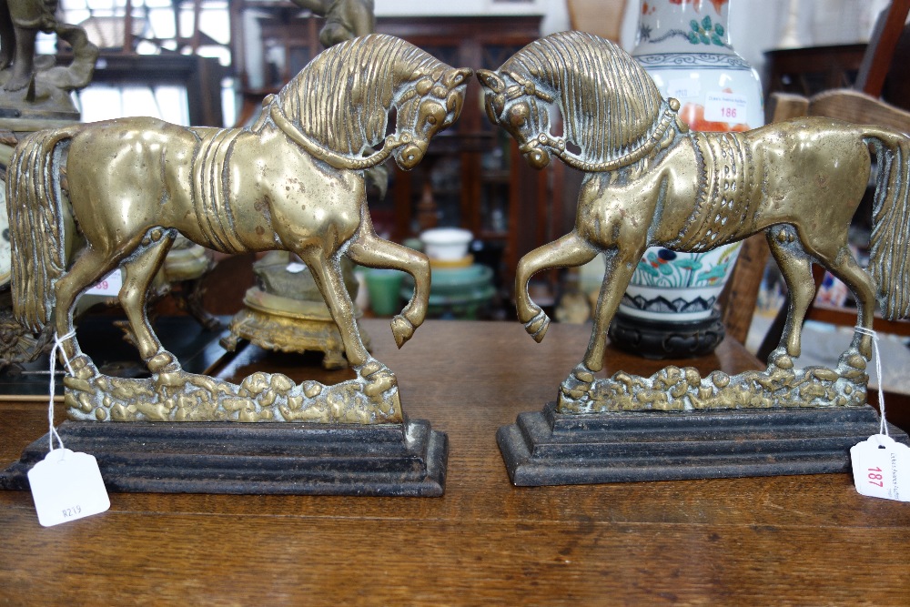 A PAIR OF VICTORIAN BRASS DOOR STOPS in the form of horses on painted iron bases