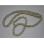 A PALE GREEN JADEITE NECKLACE, with silver clasp, 79cm long