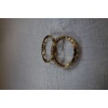 A CLEAR STONE AND UNMARKED YELLOW METAL ETERNITY RING, together with one other similar (2)