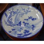 A LARGE JAPANESE BLUE AND WHITE DISH decorated with a bird amongst flowers, 47cm diam