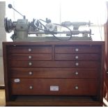 A WATCH MAKER'S LATHE by Elliott Machine Equipment Ltd London, mounted on a mahogany tool cabinet,