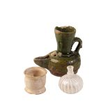 AN ISLAMIC GREEN GLAZED MEDIEVAL POTTERY OIL LAMP, a small white glazed pot with old label