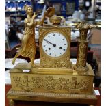 A FRENCH GILT METAL MANTEL CLOCK decorated with a figure, trophies in relief with enamel dial and