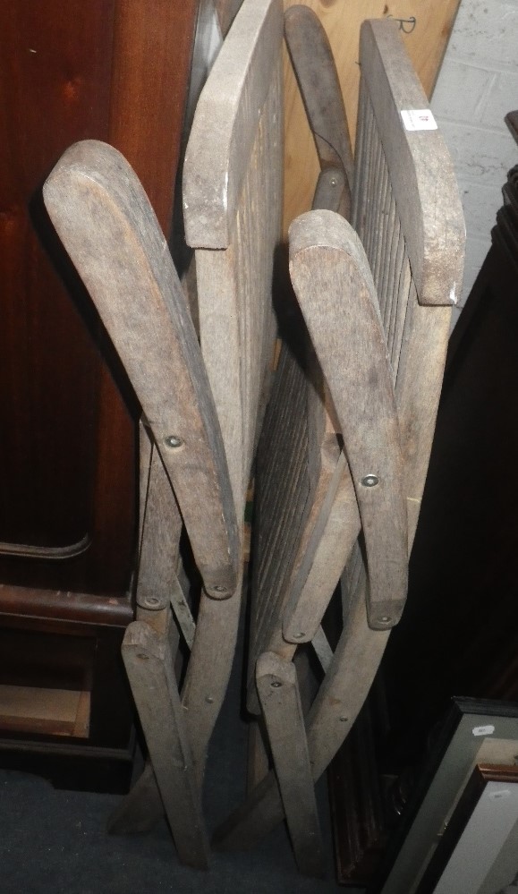 A PAIR OF WEATHERED TEAK FOLDING GARDEN CHAIRS and a pine form with metal legs