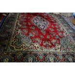 A LARGE RED GROUND CARPET with a blue border, with allover floral decoration, 297cm wide x 280cm
