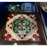 A VICTORIAN MINTON HOLLINS & CO TILE, in a period oak frame, as a teapot stand and two smaller tiles
