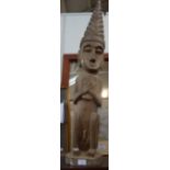 A CARVED WOODEN TRIBAL FIGURE OF A MAN WEARING A TALL HEAD DRESS with patinated finish, 100cm high