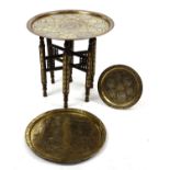 Three Middle Eastern Cairo Ware brass trays, one with table base, each having copper and silver