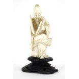 Chinese ivory carving of a seated man holding a fan with calligraphy, raised on a carved hardwood