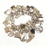 Silver charm bracelet, with large selection of mostly silver charms including windmill, wagon,