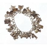 Silver charm bracelet with a large selection of mostly silver charms including wishing well, classic