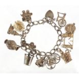Silver charm bracelet, with a selection of mostly silver charms including London Bridge, ice
