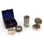 Silver items, two octagonal napkin rings, circular trinket and bottle case embossed with cherubs,