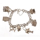 Silver charm bracelet with a selection of mostly silver charms including a cottage, handbag and