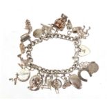 Silver charm bracelet, with a large selection of mostly silver charms including penny farthing,