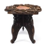 Anglo Indian folding table profusely carved in relief with flowers, 53cm high x 62cm in diameter :