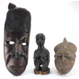 African tribal carvings including two face masks and a fertility figure, the largest 62cm in