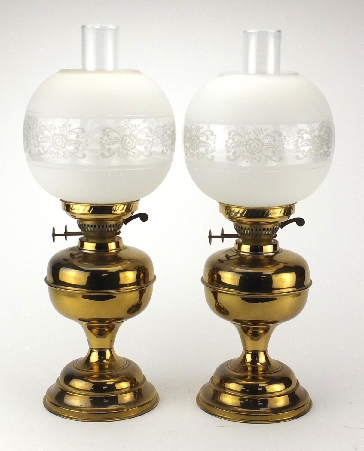 Pair of brass oil lamps with glass funnels and etched globular shades, each 51cm high : For