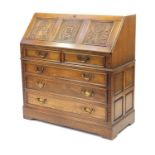 Jaycee oak bureau, carved with a crest and Tudor rose, fitted with a fall and fitted interior