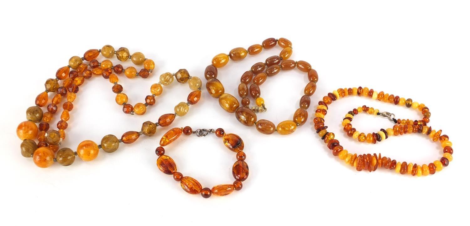 Three amber coloured bead necklaces and a bracelet, the largest 68cm in length, approximate weight
