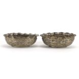 Pair of Indian unmarked silver bowls, each embossed with lions chasing antelope, each 12cm wide,