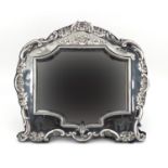 Large silver easel mirror with bevelled glass and embossed with shells and swags, indistinct