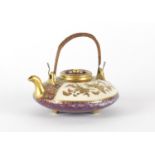 Japanese Satsuma pottery squatted teapot with swing handle, hand painted and gilded with panels of