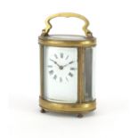 Oval brass cased carriage clock with enamelled dial and Roman numerals, 12cm high :For Further