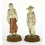 Pair of Indian carved ivory figures raised on circular wood stands, the largest 16cm high :For