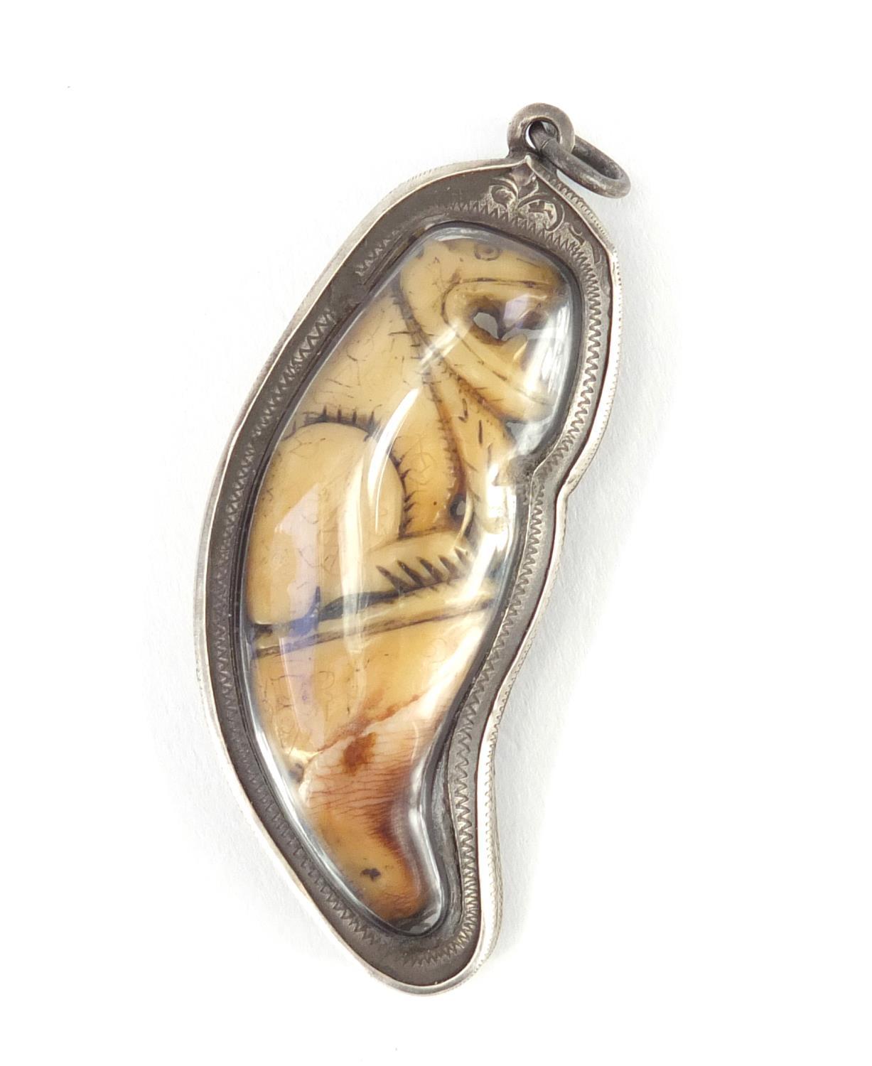 Ivory tooth carved with a mythical animal, encased in a silver coloured metal pendant mount, overall - Image 2 of 3