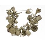 Silver charm bracelet with a large selection of mostly silver charms including penny farthing,