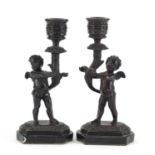 Pair of classical patinated bronze putti design candlesticks raised on marble bases, each 18cm