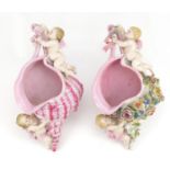 Two continental porcelain wall pockets in the form of cornucopia shells with putti, 30cm high :For