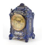 French pottery mantel clock striking on a gong gilded with flowers, the ornate brass dial with