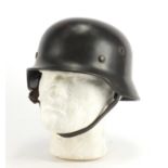 German Military interest tin helmet with decal and leather liner, impressed marks to the interior :